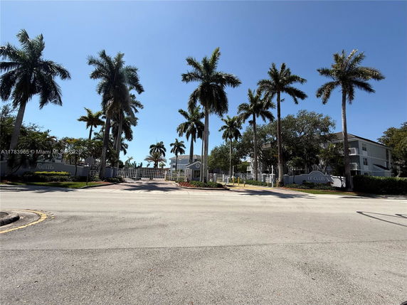 Front view of a gated residential complex with palm trees.