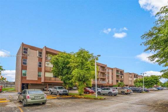 Front view of a multi-story residential building with parking spaces.