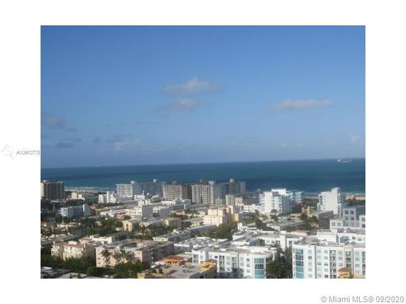 Panoramic view of a cityscape with multiple buildings and an ocean in the background.