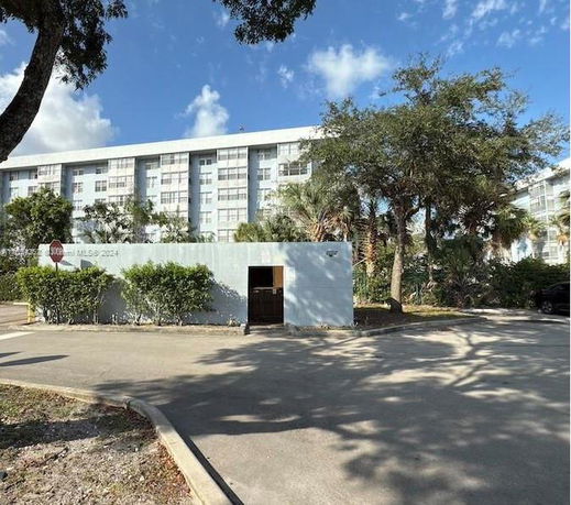 Front view of a multi-story residential building with a small structure in the foreground.