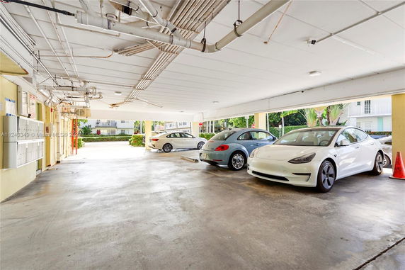 Covered parking area with multiple cars parked.