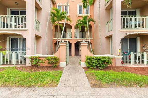 Front view of an apartment building with balconies and palm trees.