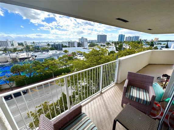 View from a balcony showing an urban landscape with buildings and trees.