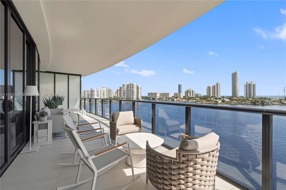 Panoramic view from a building's balcony overlooking a waterfront and city skyline.