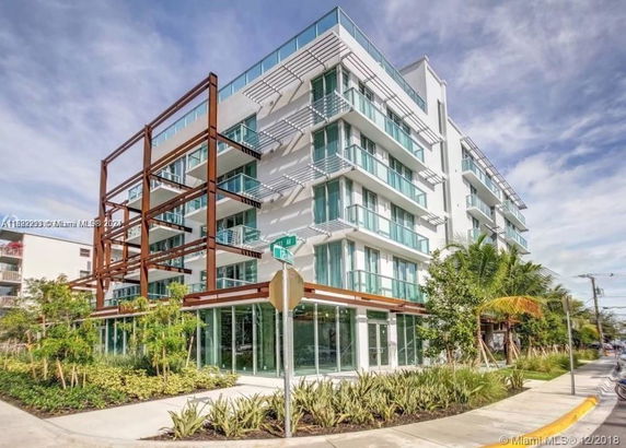 Front view of a modern multi-story building with glass balconies.