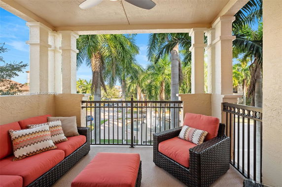 Balcony view with outdoor seating and palm trees in the background.