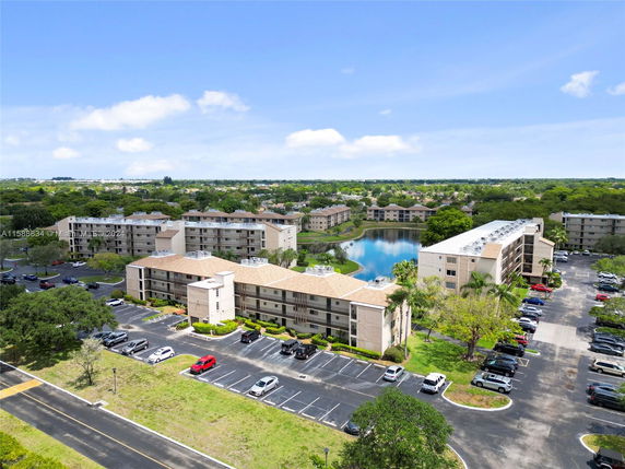Aerial view of apartment complex with parking lots and a pond in the background.