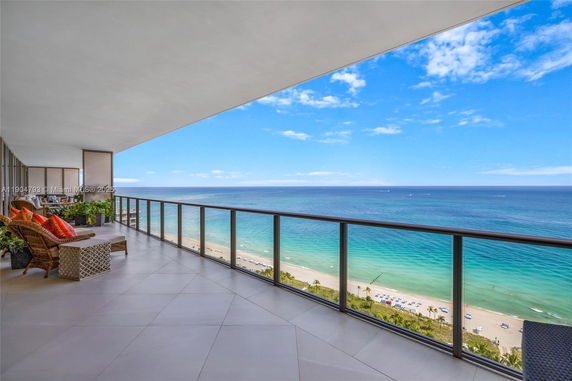 Wide-angle view from a balcony overlooking the ocean and beach.