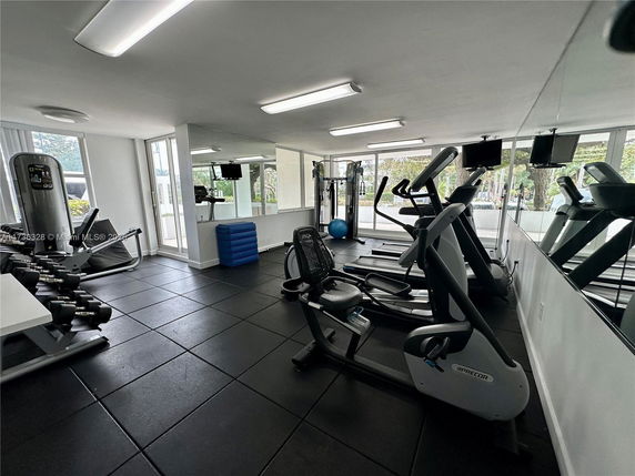 Indoor gym area with exercise equipment including treadmills, exercise bikes, and weights.