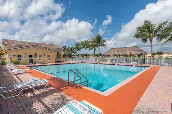 Outdoor swimming pool with lounge chairs and a small building nearby.