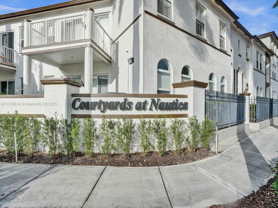 Front view of a two-story residential building with balconies and a sign reading 'Courtyards at Nautica'.