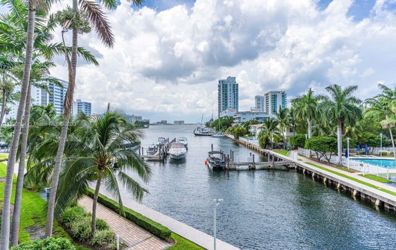 View of waterfront area with boats docked and tall buildings in the background.