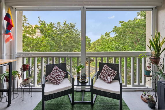 View from a balcony with chairs overlooking trees and partially visible parking lot.