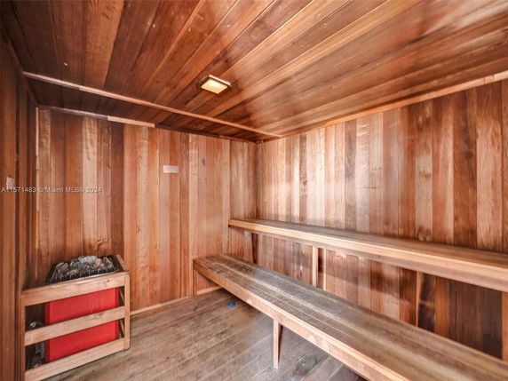 Wooden sauna room with benches and a heating unit.