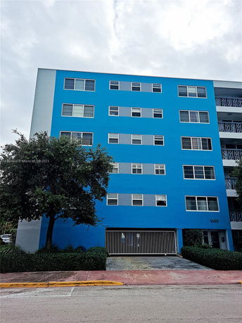 Front view of a multi-story blue building with multiple windows.