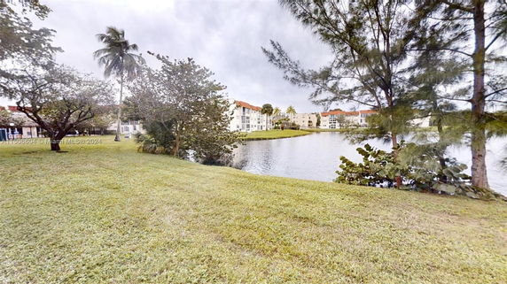 View of lakeside residential buildings surrounded by trees and water.