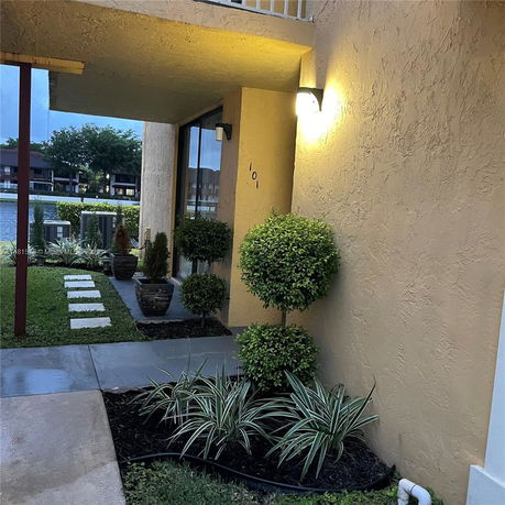 Partial view of a building entrance with outdoor plants and pathway.