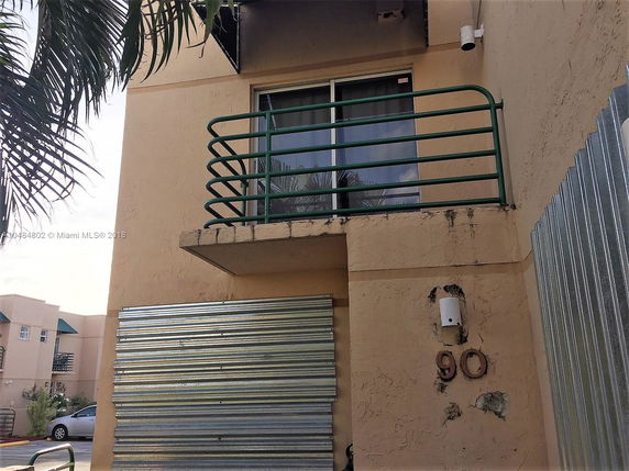 Front view of a multi-story building with a small balcony and metal siding.