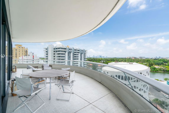 Panoramic view from a balcony overlooking modern buildings and greenery.