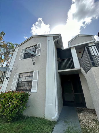 Front view of a two-story building with white shutters and a satellite dish.