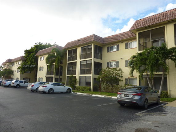 Front view of a multi-story apartment building with a parking area in front.