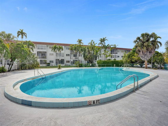 Outdoor swimming pool in front of a multi-story residential building.