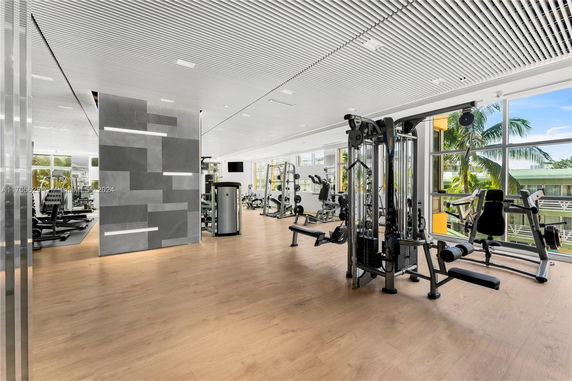 Interior view of a modern fitness gym with various exercise equipment and large windows.