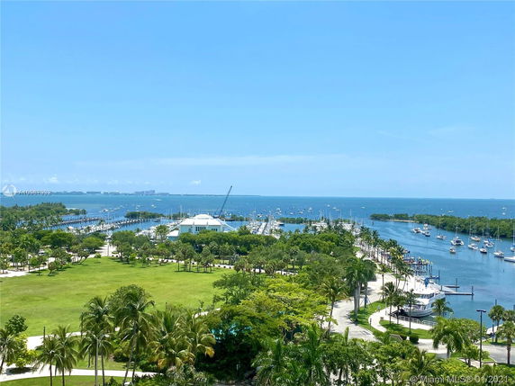 Panoramic view of a marina with boats and green park areas, overlooking a body of water on a clear day.