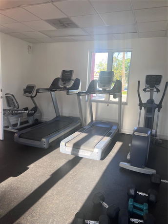 Room with gym equipment including treadmills and exercise machines.