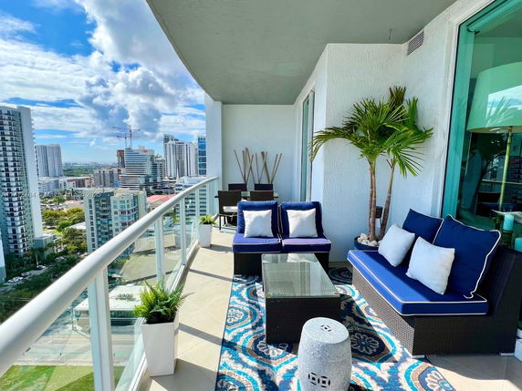 Balcony with seating area offering a panoramic view of cityscape and skyscrapers.
