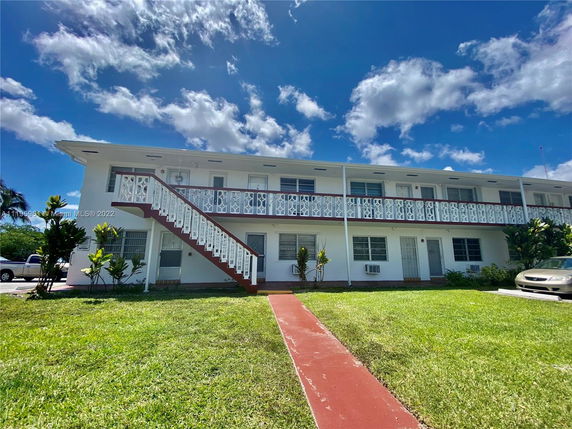 Front view of a two-story building with exterior staircases and railing.