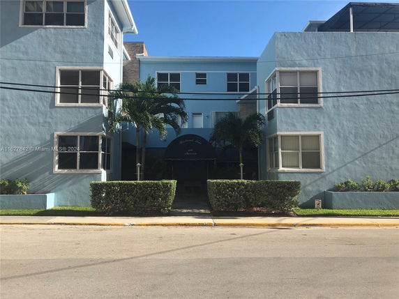 Front view of a blue, two-story apartment building with white window frames.