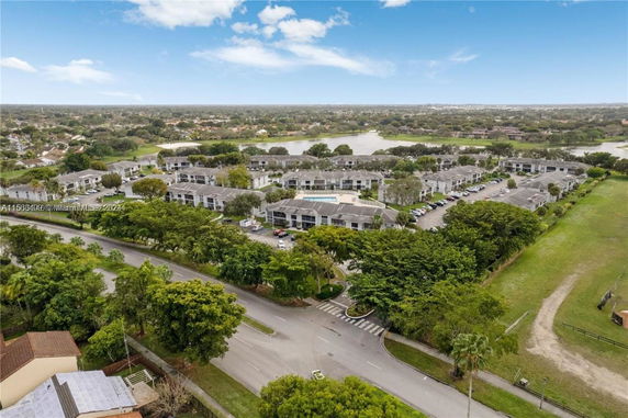 Aerial view of a residential complex with multiple buildings surrounded by greenery and roads.