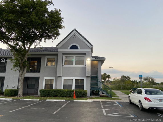 Front view of a two-story residential building with a tiled roof and exterior staircase.