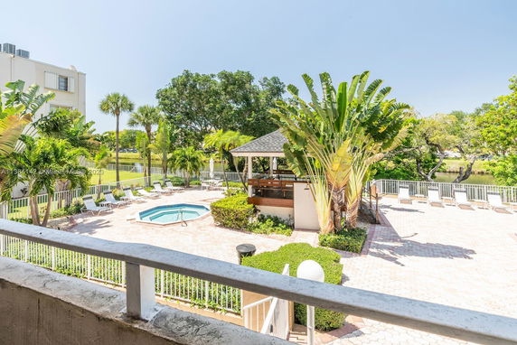 Outdoor area with a swimming pool, surrounded by lounge chairs and tropical plants.