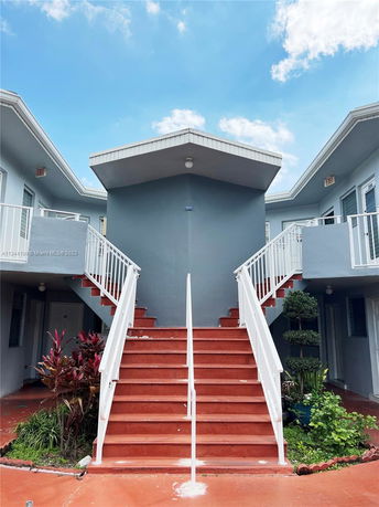 Front view of a two-story building with red stairs and white railings.