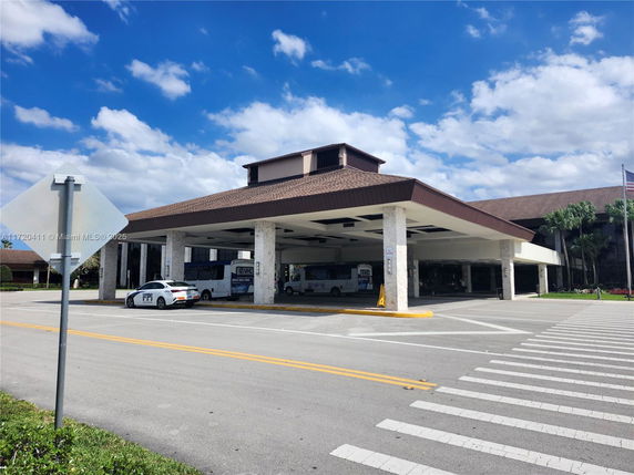 Front view of a building with a large covered entrance and parking area.