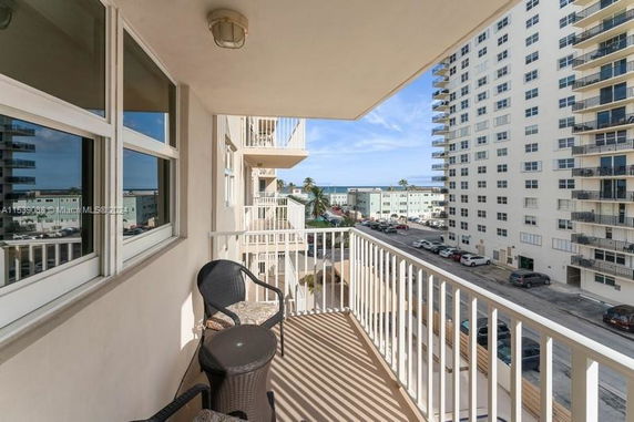 View from a balcony overlooking adjacent buildings and a distant view of the ocean.