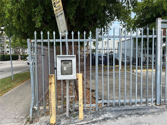 Outdoor parking area with a metal fence and security gate.