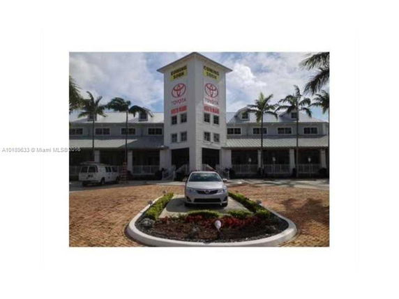 Front view of a commercial building with a central tower and parking area.