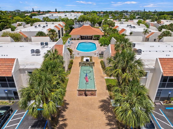 Aerial view of a residential area with a central swimming pool and surrounding buildings.