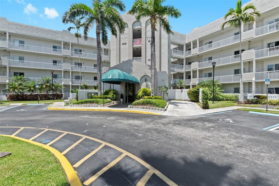 Front view of a multi-story residential building with balconies and a covered entrance.