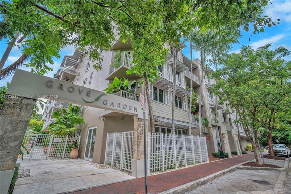 Front view of a multi-story residential building with balconies and a gated entrance.