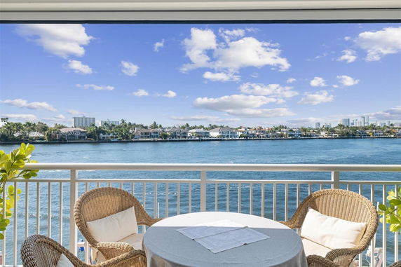 Panoramic view from a balcony overlooking a body of water and distant houses.