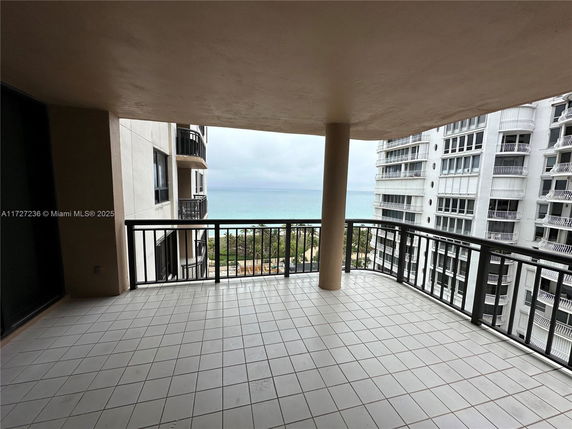 Balcony view with railings, overlooking buildings and the ocean.