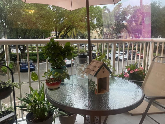View from a balcony overlooking a parking lot with several cars and trees.