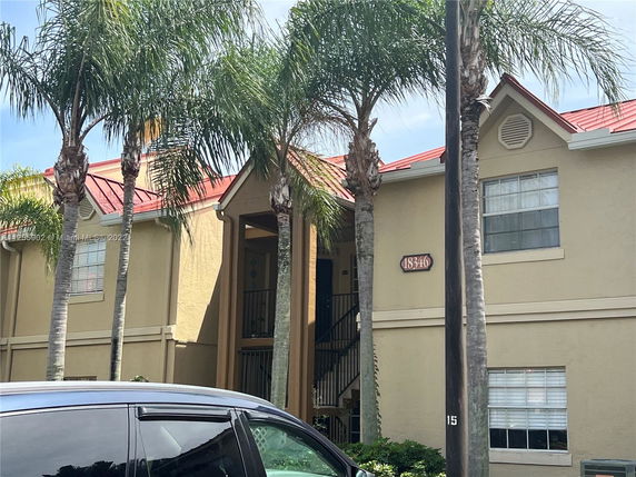 Front view of a multi-story building with red roof and palm trees.