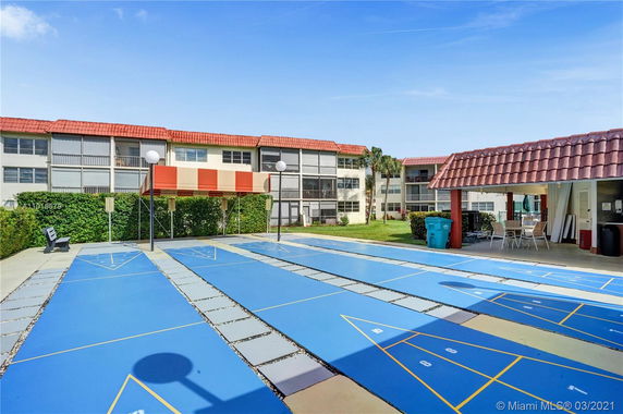 Outdoor area featuring a shuffleboard court in front of residential buildings.