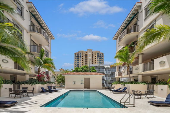 Outdoor swimming pool area between two multi-story apartment buildings.
