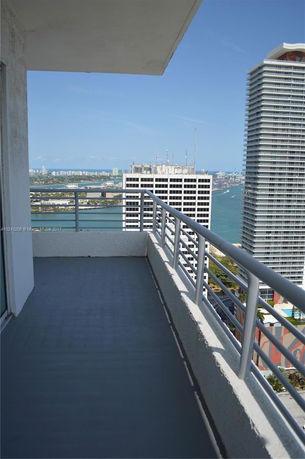 View from a balcony showing a high-rise building and a distant cityscape with water.